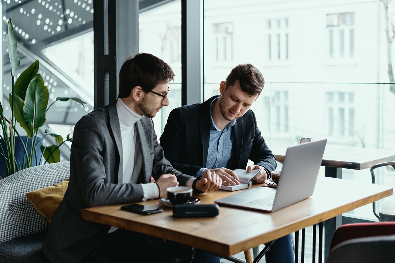 Two young businessman having a successful meeting at restaurant. - Kickstart Bahrain Business owners reviewing company setup documents in Bahrain